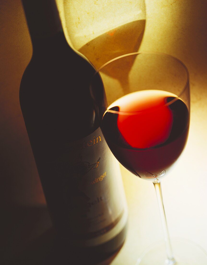 Still life: red wine glass in front of labelled red wine bottle