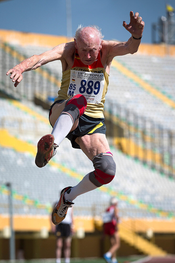 Elderly male athlete jumping mid-air