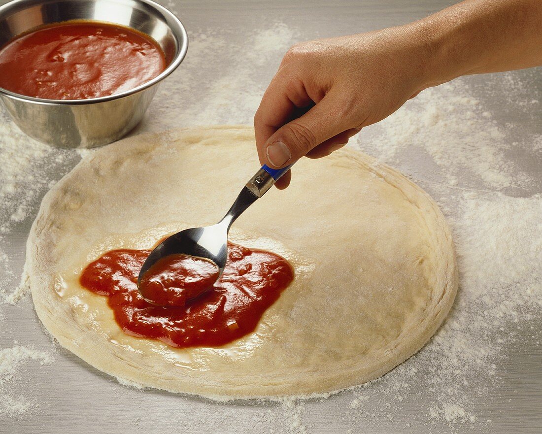 Pizza mit Tomatensauce bestreichen