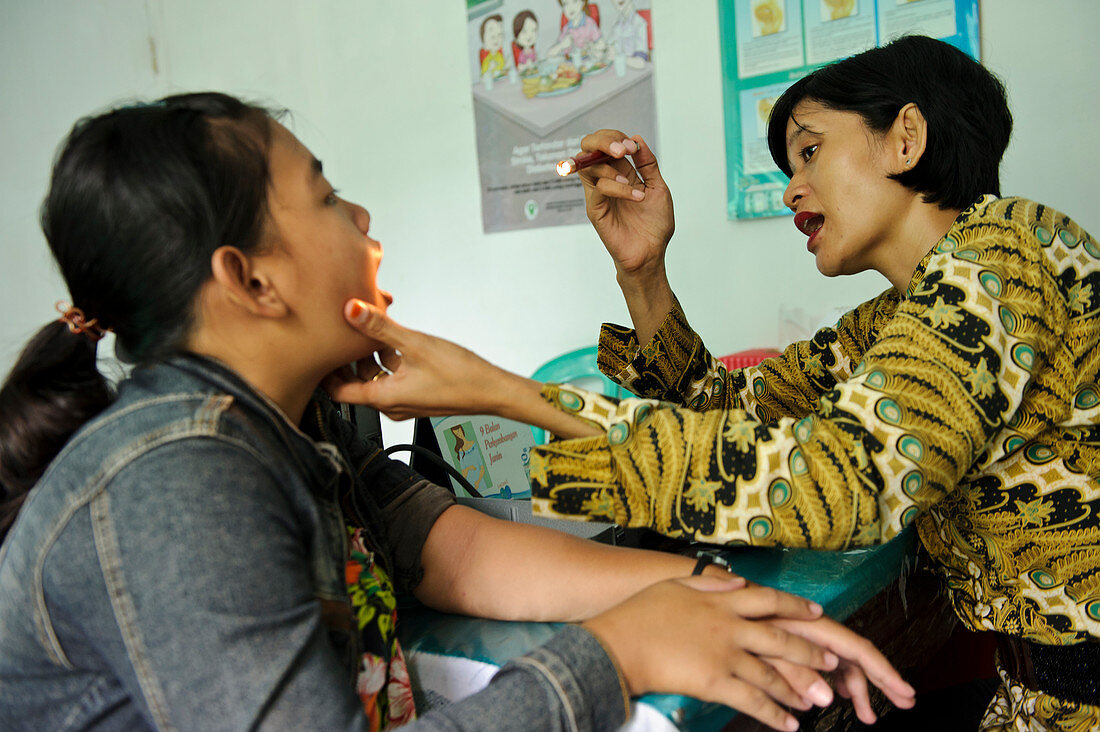 Doctor examining girl's throat,Indonesia