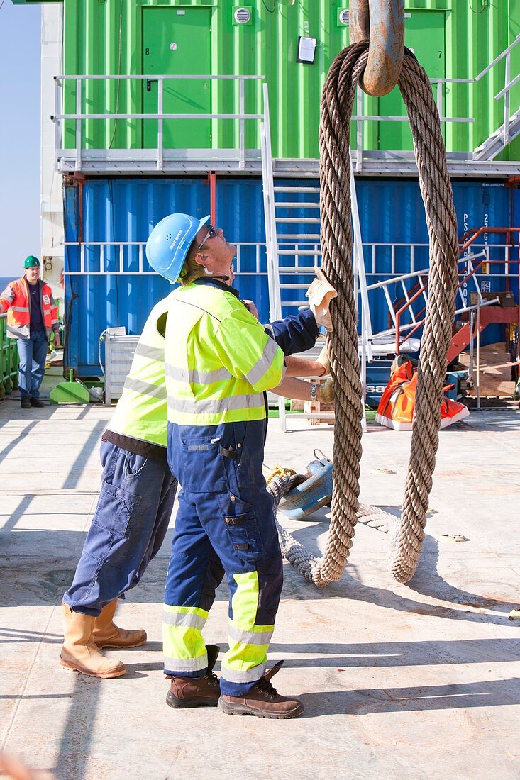 Workers next to a crane hook