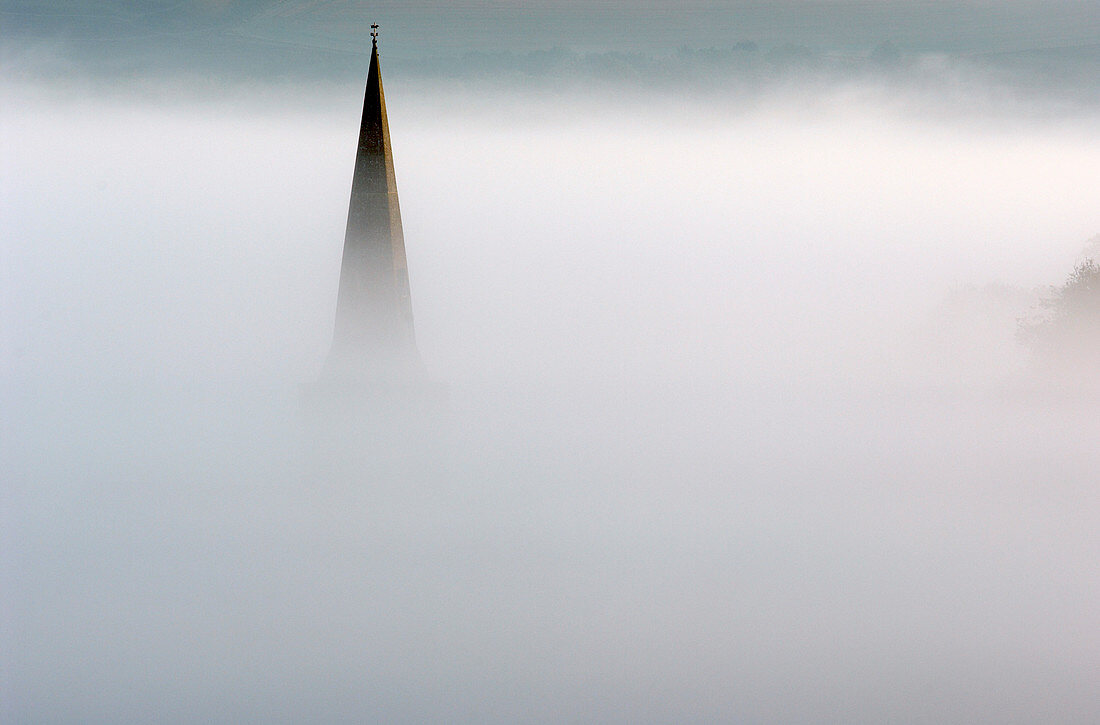 Church spire in dense fog