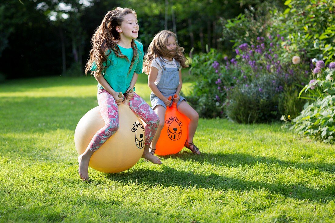 Two sisters bouncing on bouncy hoppers