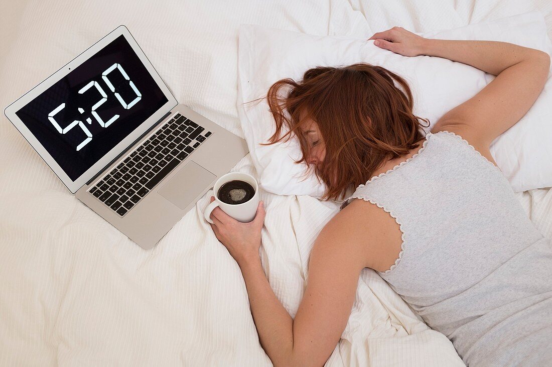 Exhausted woman in bed with laptop