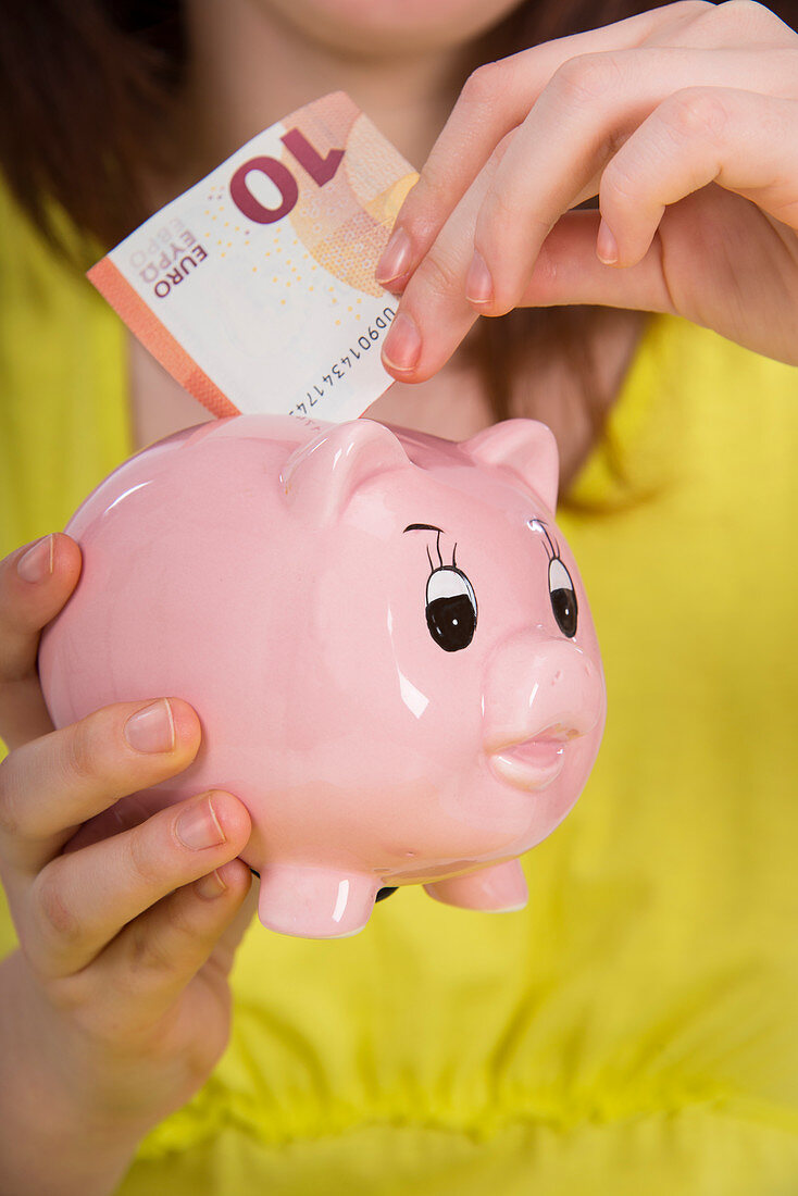 Girl saving euros in piggy bank