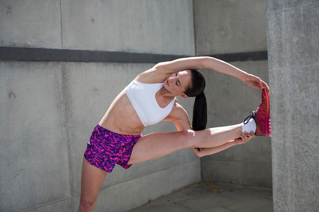 Woman stretching against wall