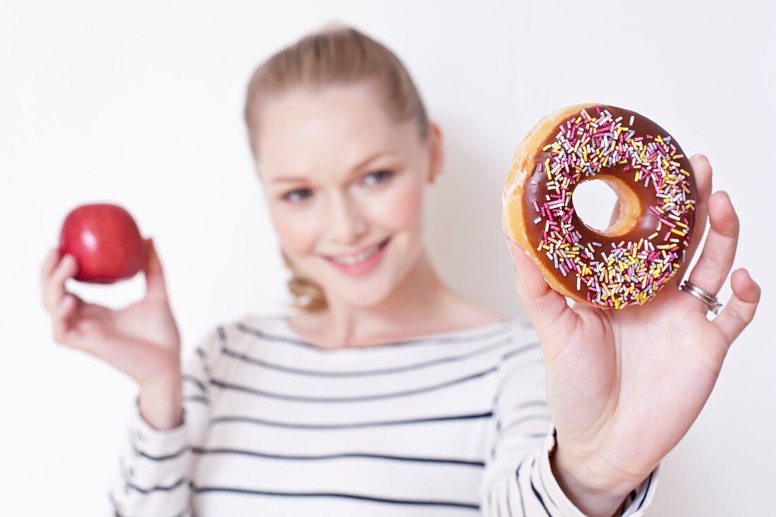Pregnant woman holding apple and doughnut