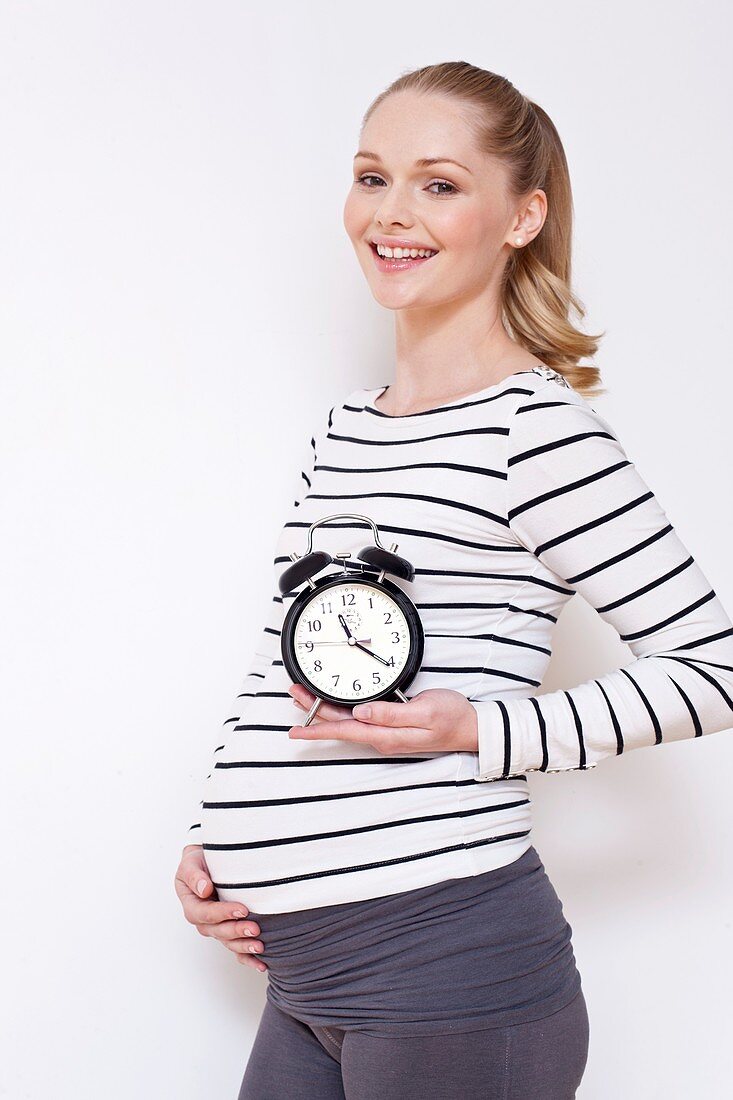 Pregnant woman holding alarm clock