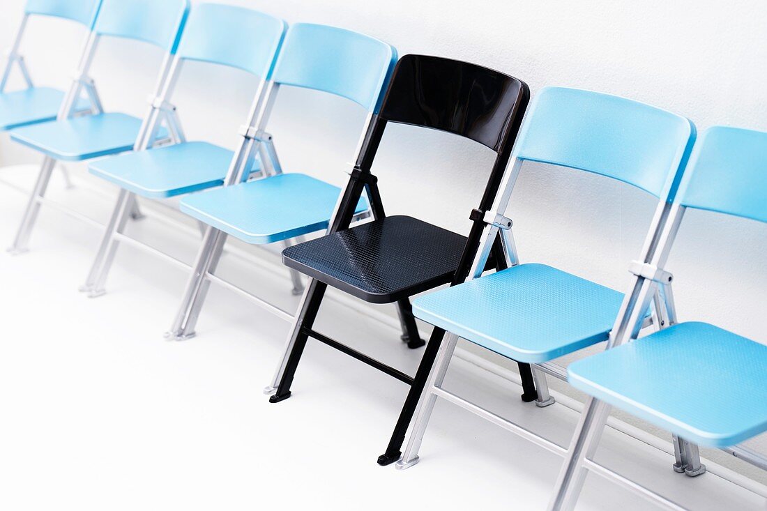 One black chair in a row of blue chairs