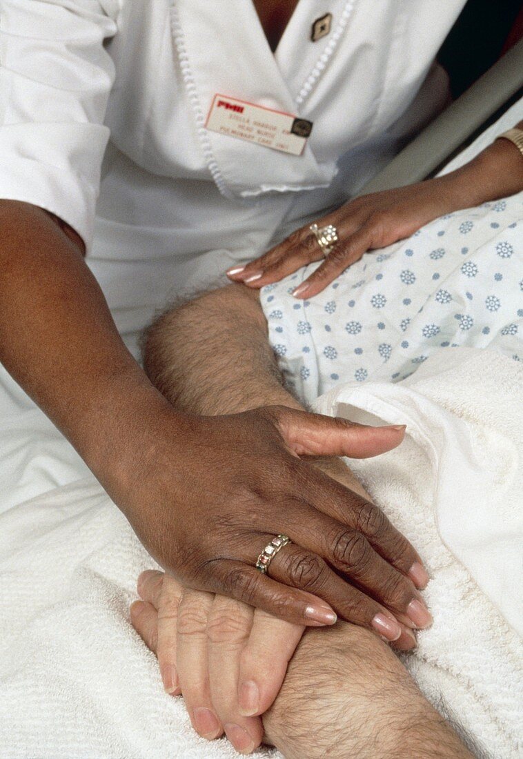 Nurse touching hands of elderly male patient