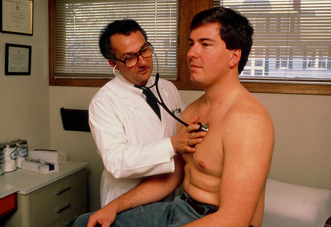 Doctor using a stethoscope to examine male patient