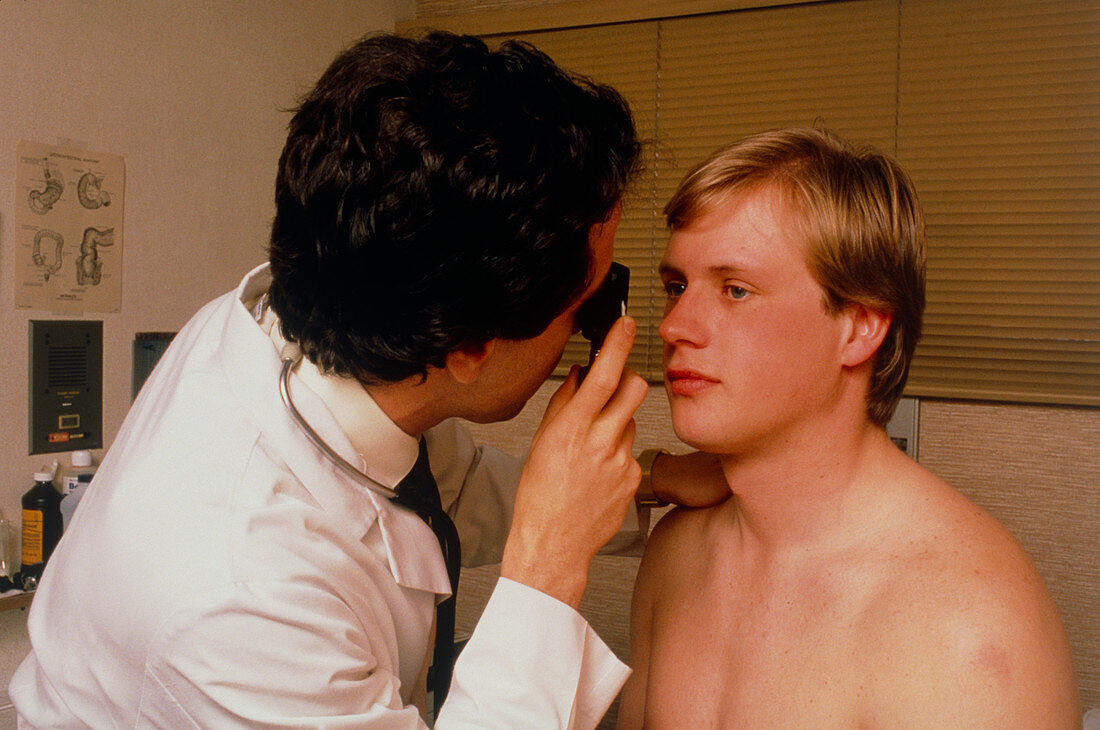 Doctor examining man eye with hand ophthalmoscope