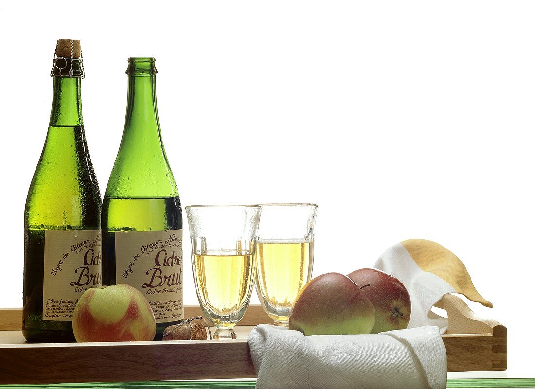 Two bottles and two glasses of French cider on tray