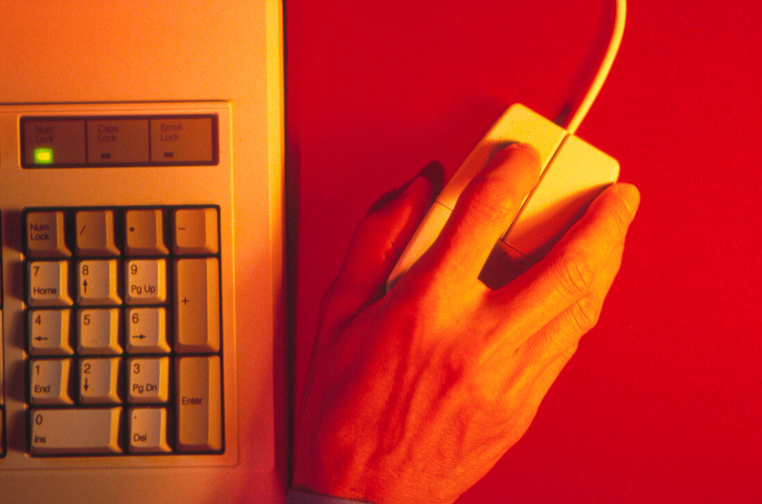 Hand operates a computer mouse beside a keyboard