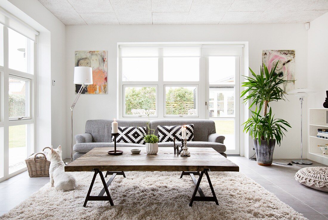 Rustic coffee table made from reclaimed wood and grey couch in front of French windows in living room