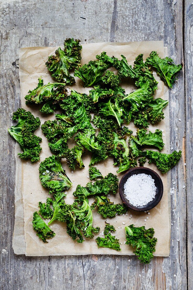 Curly kale chips with coarse salt on baking paper