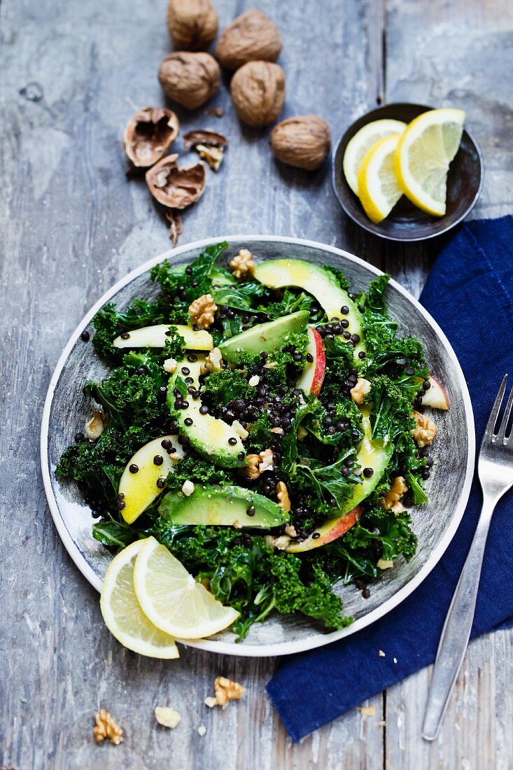 A curly kale salad with avocado, apple, walnut and black lentils
