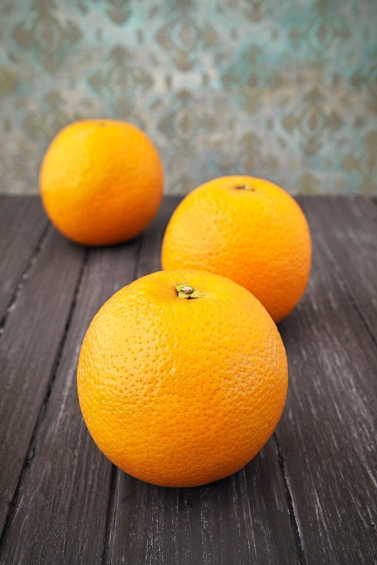 Three oranges on a wooden surface