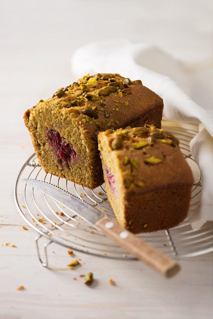 Pistachio and raspberry cake on a cooling rack