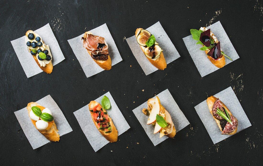 Italienische Crostini mit verschiedenen Belägen auf weißem Backpapier