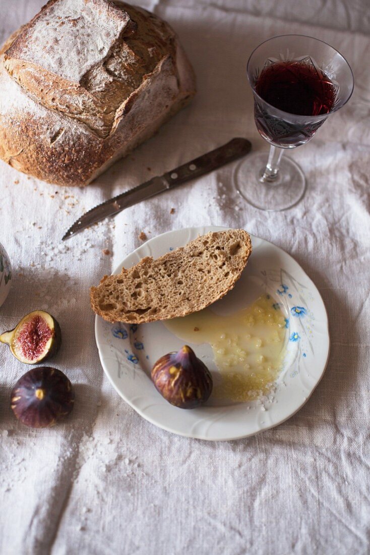 Roggenbrot, Olivenöl, Meersalz, ein Glas Rotwein und frische Feigen