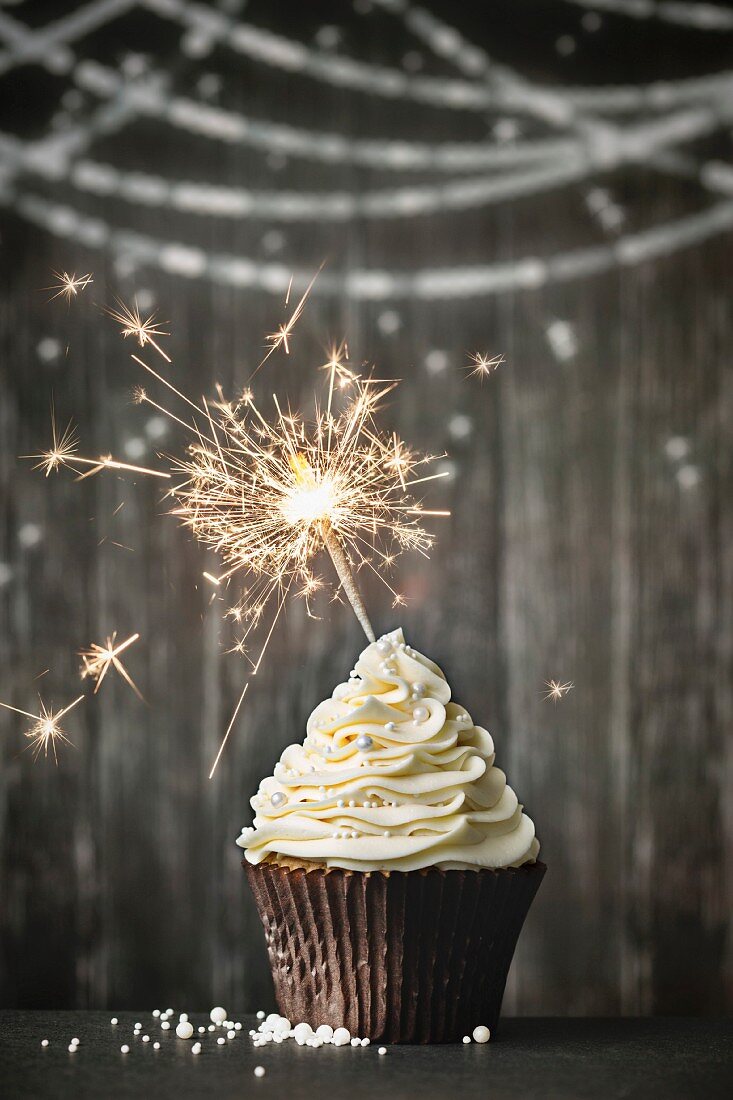 Cupcake with sparkler against a wooden background