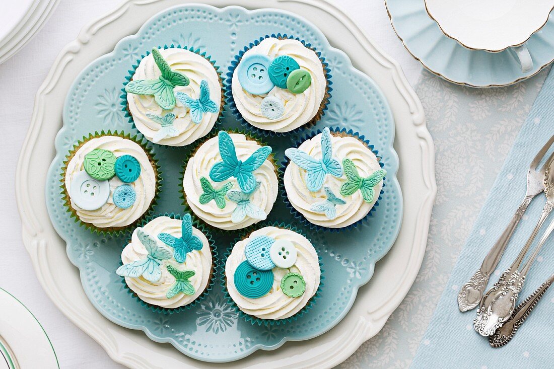Cupcakes mit Zucker- Schmetterlingen und Knöpfen verziert