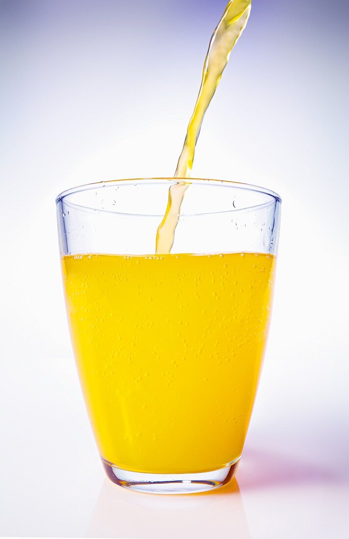 Orangensaft in Glas einschenken