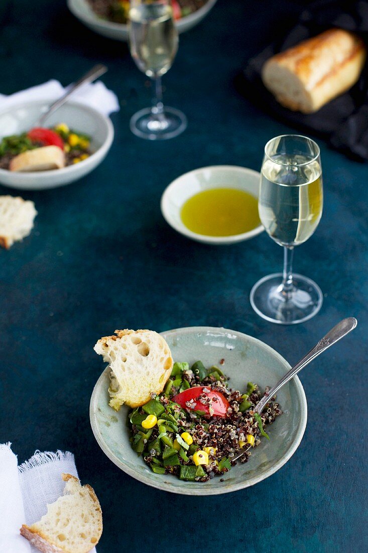 Gebratene Poblano-Quinoa mit Maiskörnern, Tomaten und Koriander, serviert mit Weißwein, Olivenöl und Brot