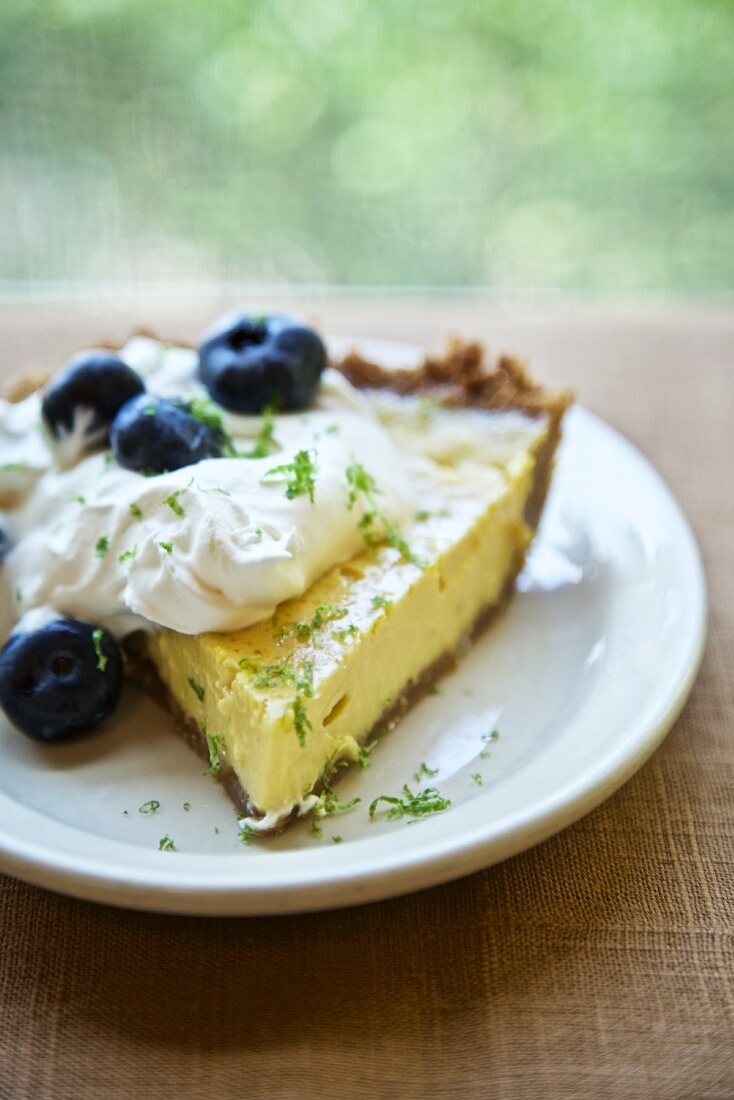 A slice of pumpkin pie with whipped cream and bluberries