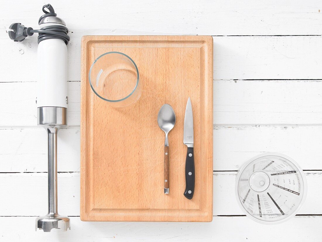 Kitchen utensils: a hand blender, a glass, cutlery and a measuring cup