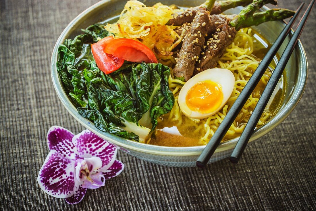 Japanese ramen soup with beef and asparagus rolls and egg