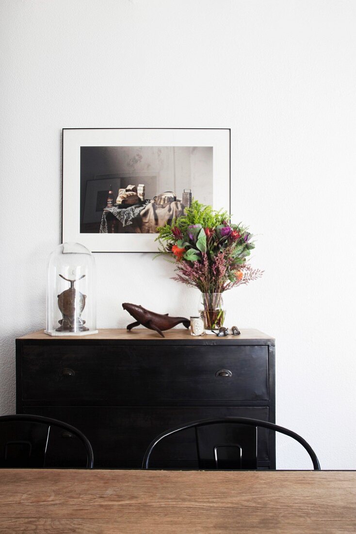 Flowers on dark chest of drawers in dining area