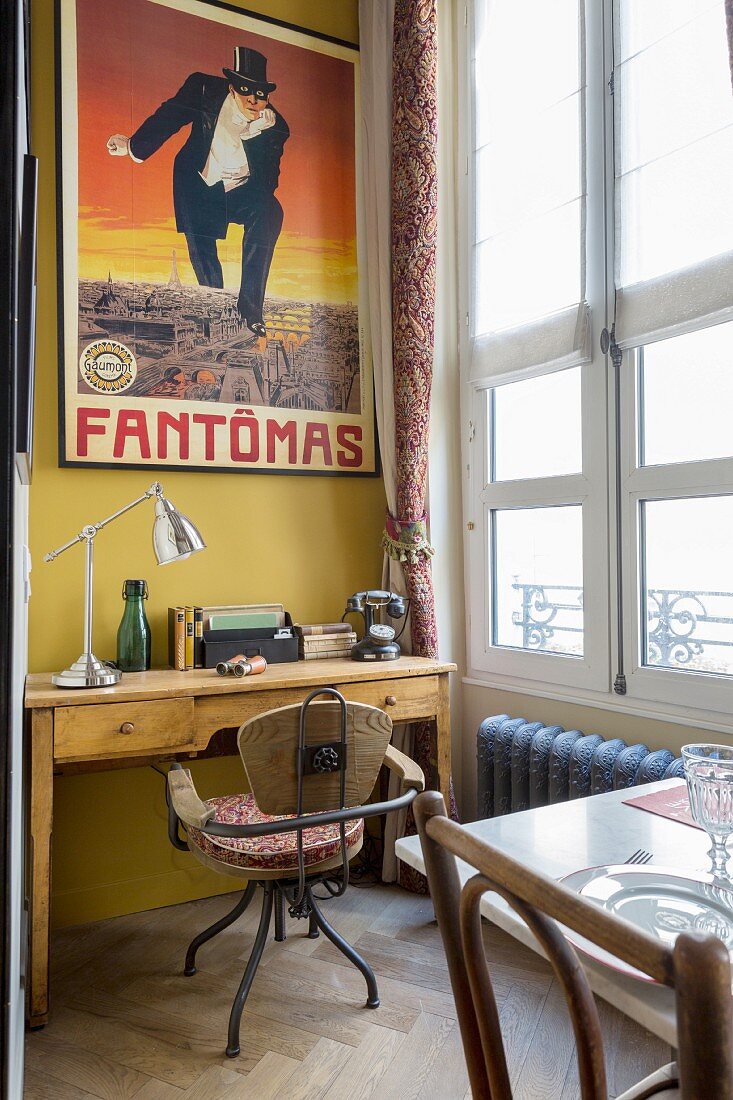 Desk below retro poster on mustard-yellow wall