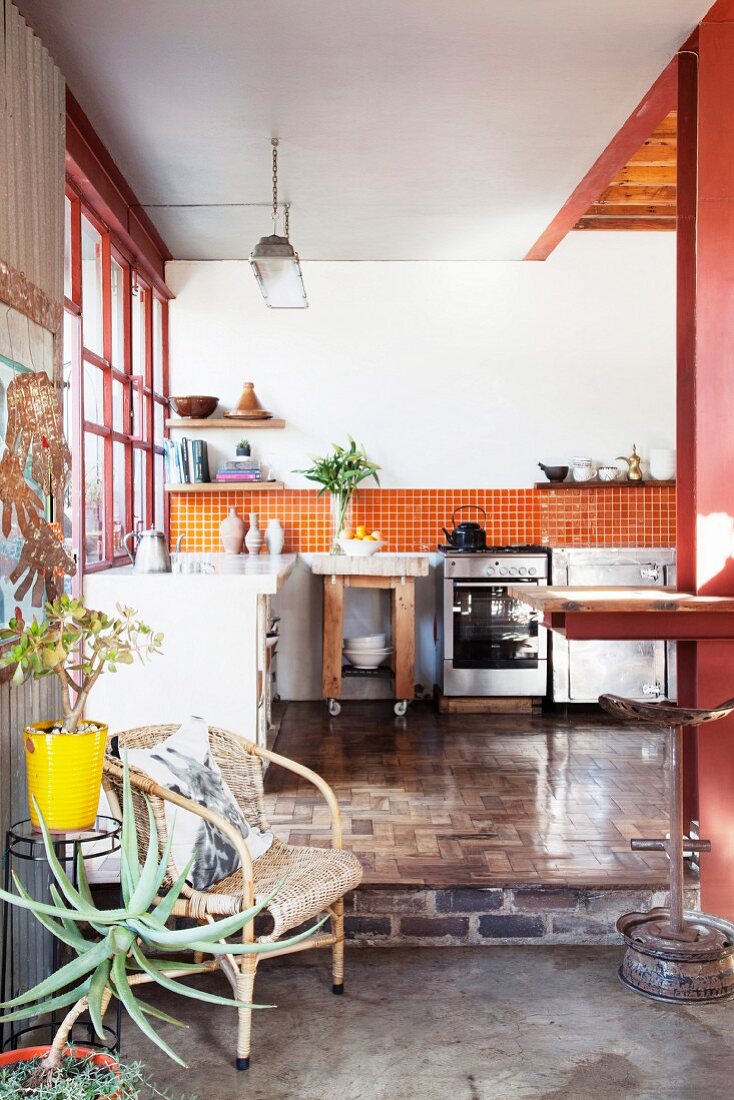Offener Küchenbereich mit recyceltem Parkettboden und orangefarbenen Wandfliesen in Loftwohnung