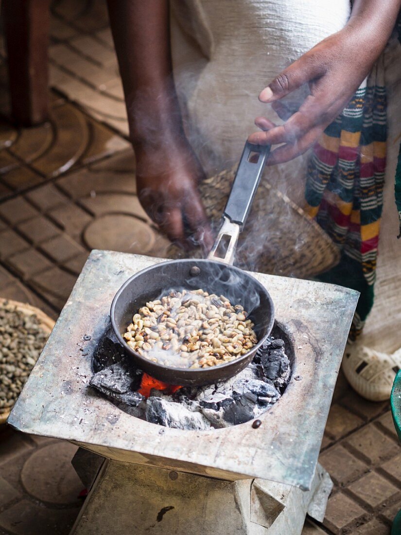 A woman roasting green coffee beans during a traditional coffee ceremony in Ethiopia