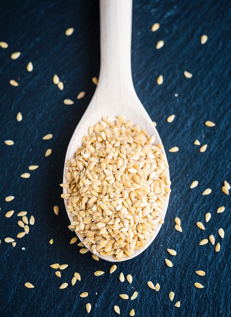 Golden flax seeds on a wooden spoon (seen from above)