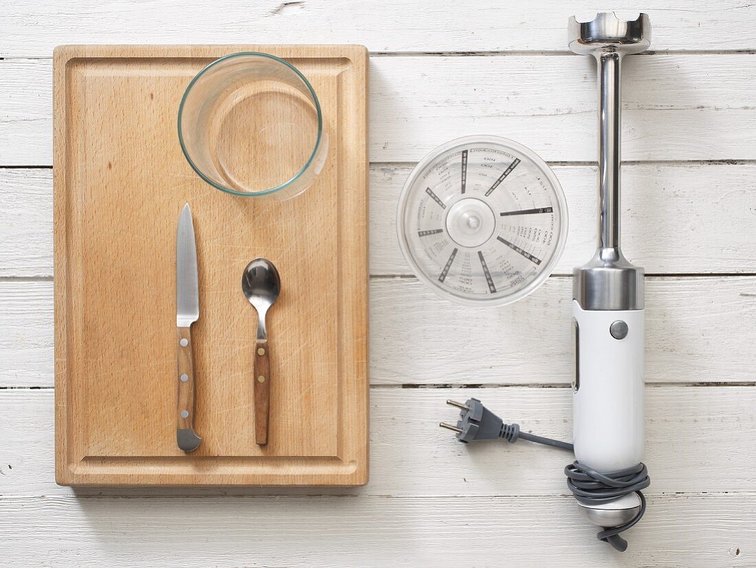 Kitchen utensils: a hand blender, measuring cup, cutlery and a glass