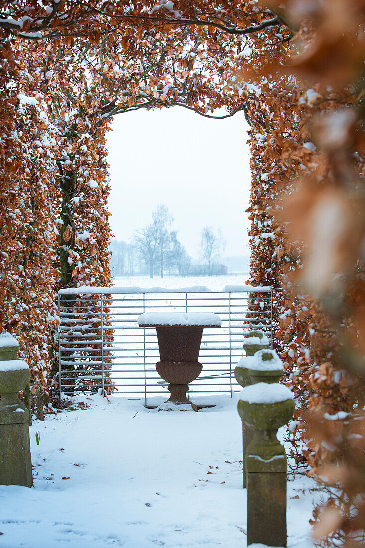 Blick auf Laubengang, verschneiten Garten und Steinvase