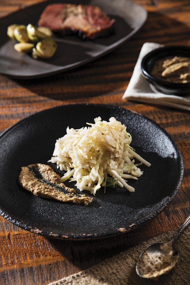 Home-made sauerkraut and mustard on a black plate