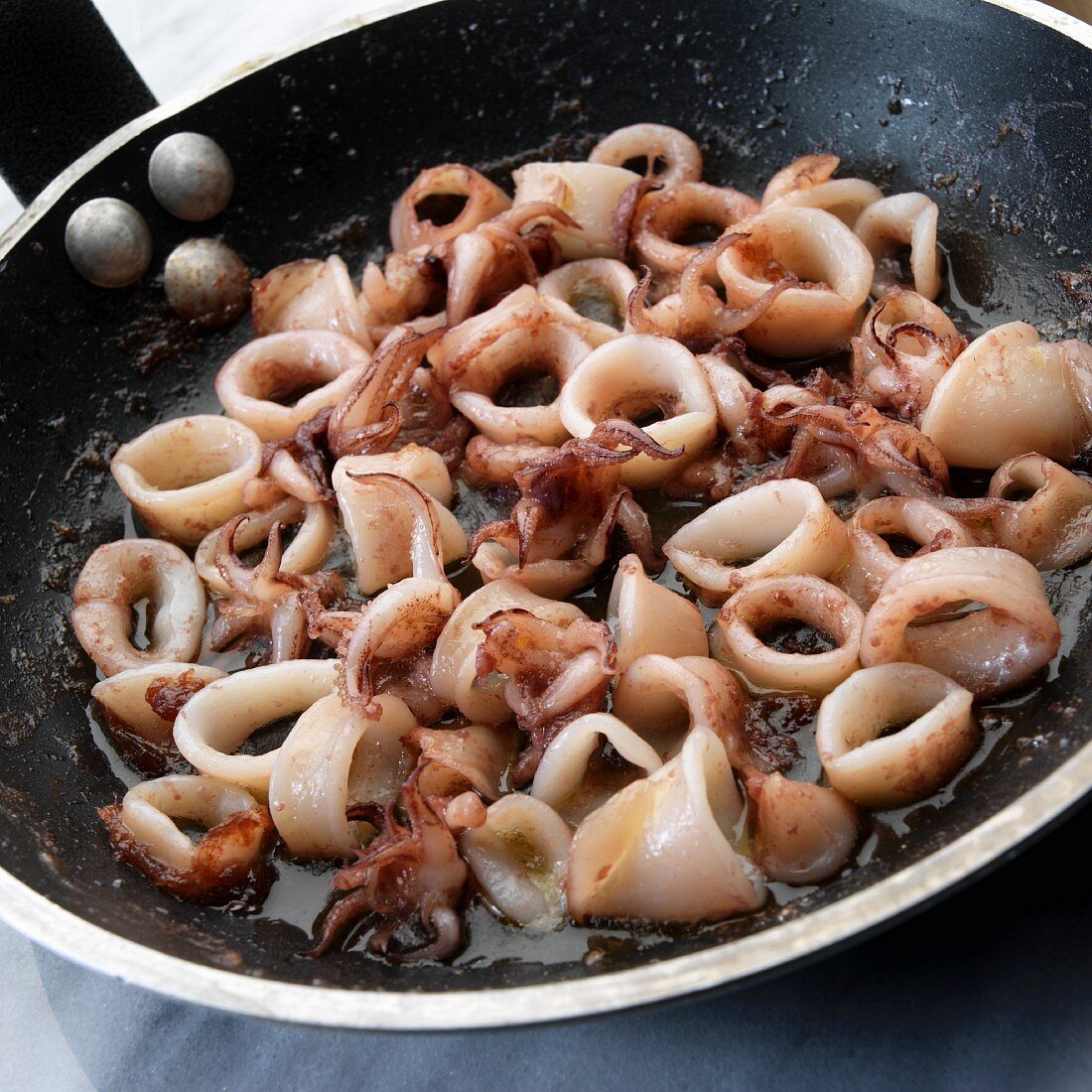 Pan-fried calamari rings in a frying pan