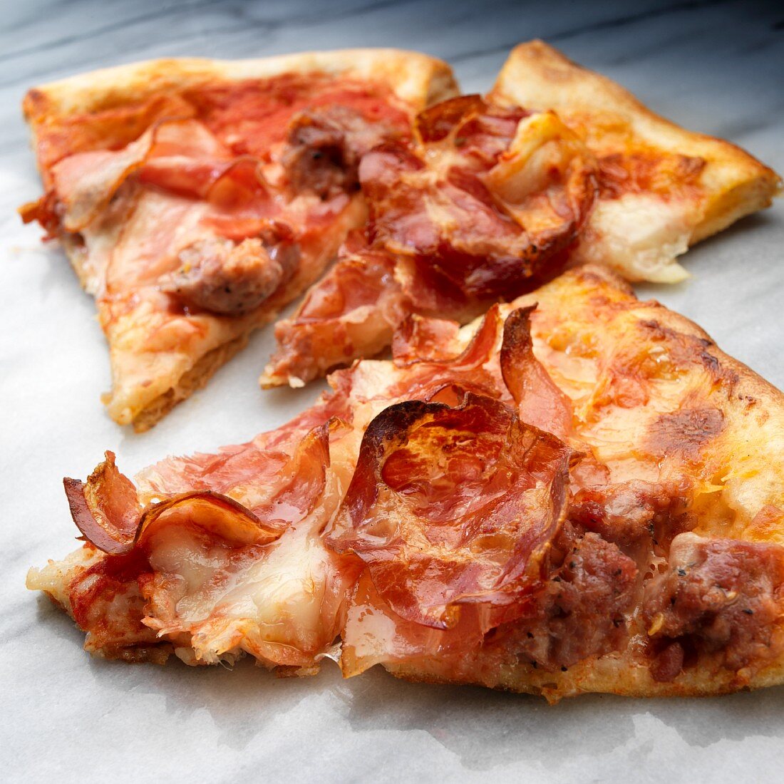 Slices of pizza with sausage, coppa and Prosciutto