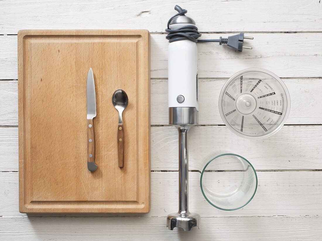 A hand blender, knife, spoon, glass and measuring cup