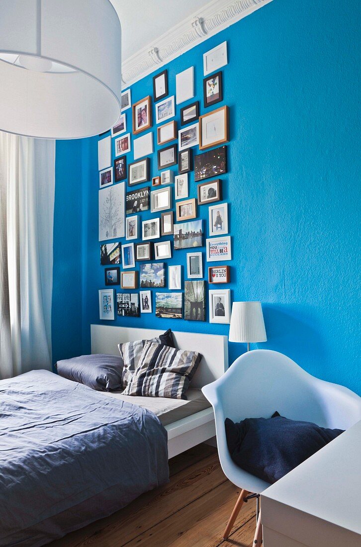 Various framed photos hung in salon style on blue bedroom wall