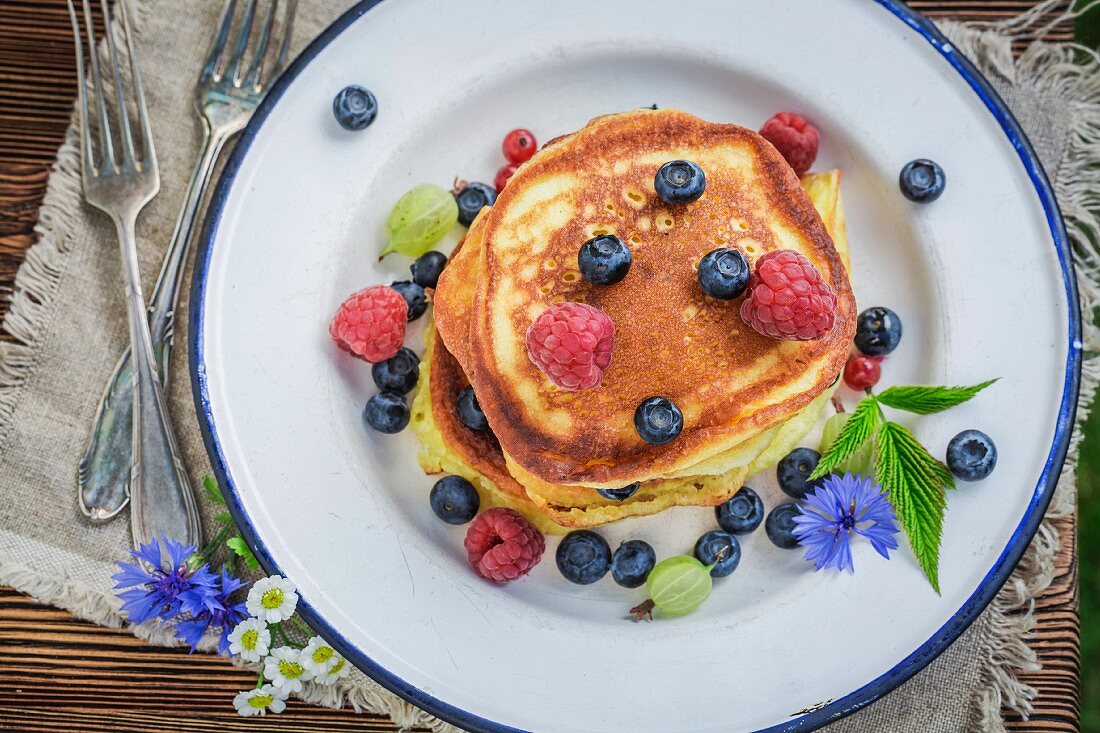 Gestapelte Pancakes mit frischen Beeren und Ahornsirup (Draufsicht)