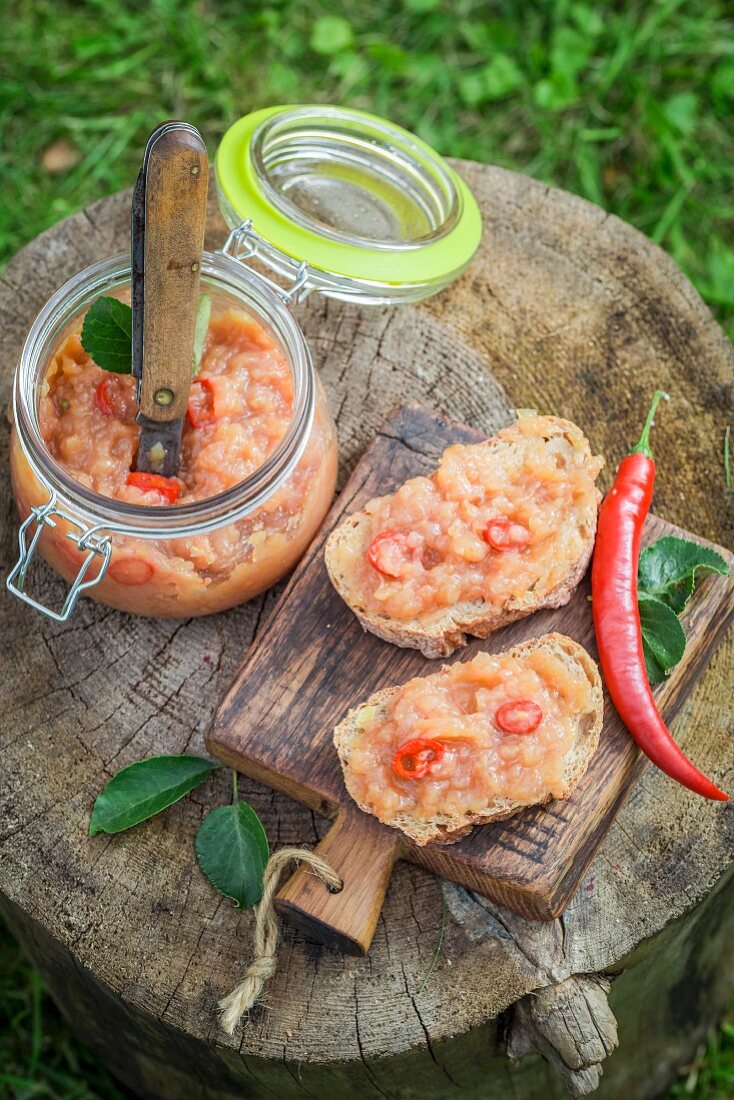 Bread topped with apple and chilli jam on a wooden board in the garden