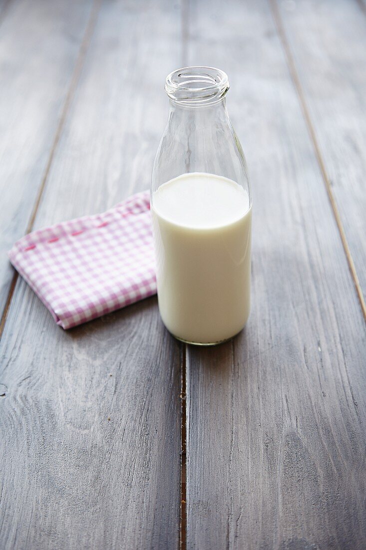A bottle of milk in front of a checked tea towel