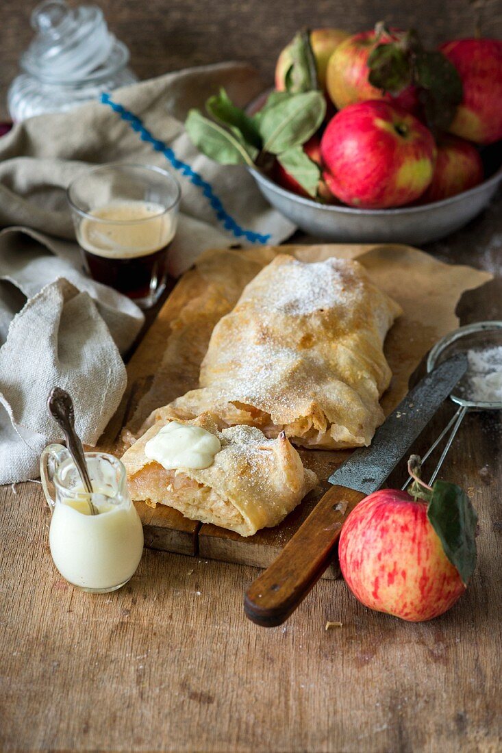 Apfelstrudel mit Sahne auf Holzbrett