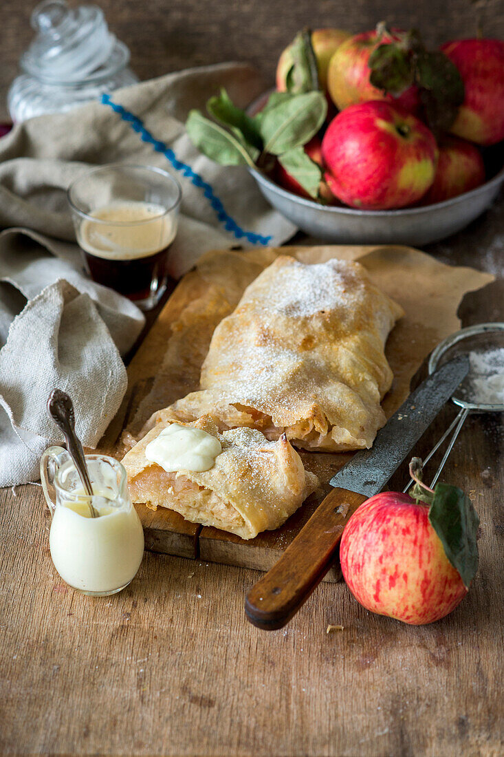 Apple strudel with cream on a wooden board