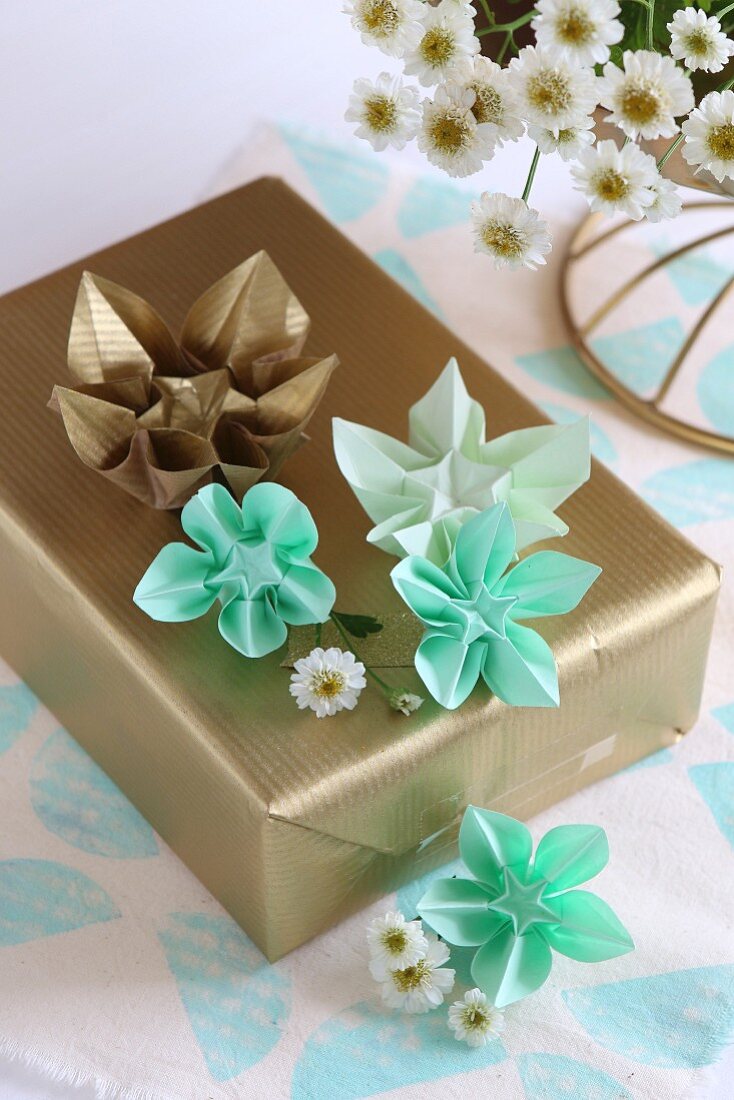 Origamisterne auf einem golden verpackten Geschenk